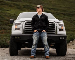Senior boy wearing hat standing tall and proud in front of his Ford pick up truck during his photos session.