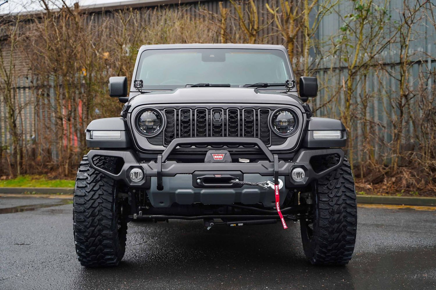 Front view of modified Jeep Wrangler with custom bumper and off-road accessories.