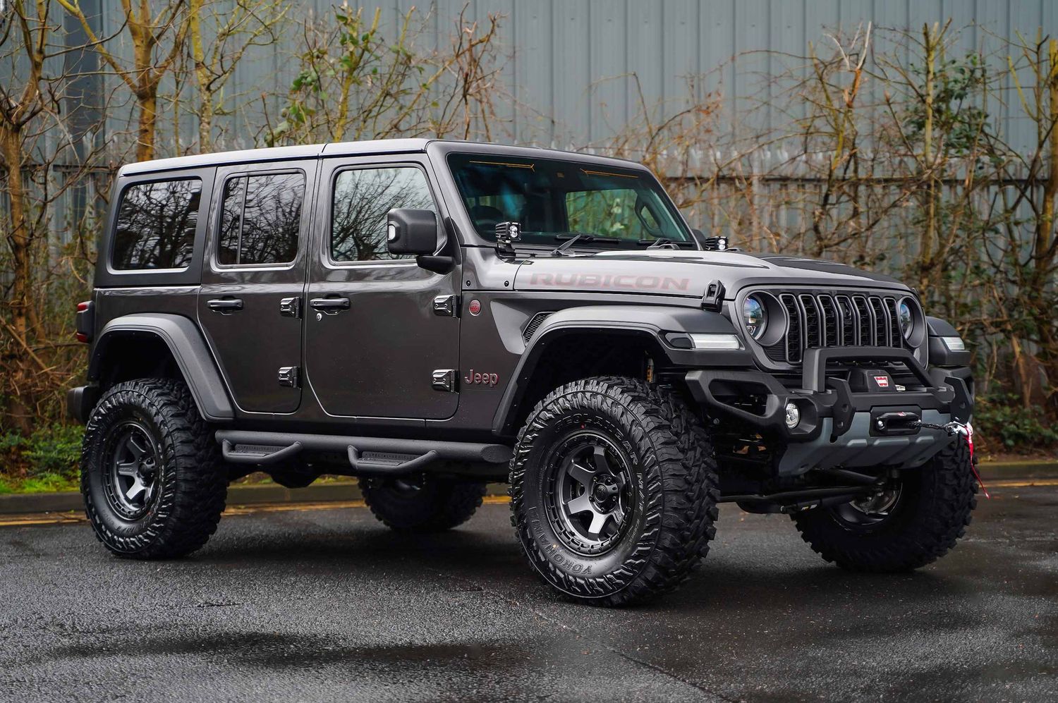 Side profile of lifted silver Jeep Wrangler with off-road modifications.