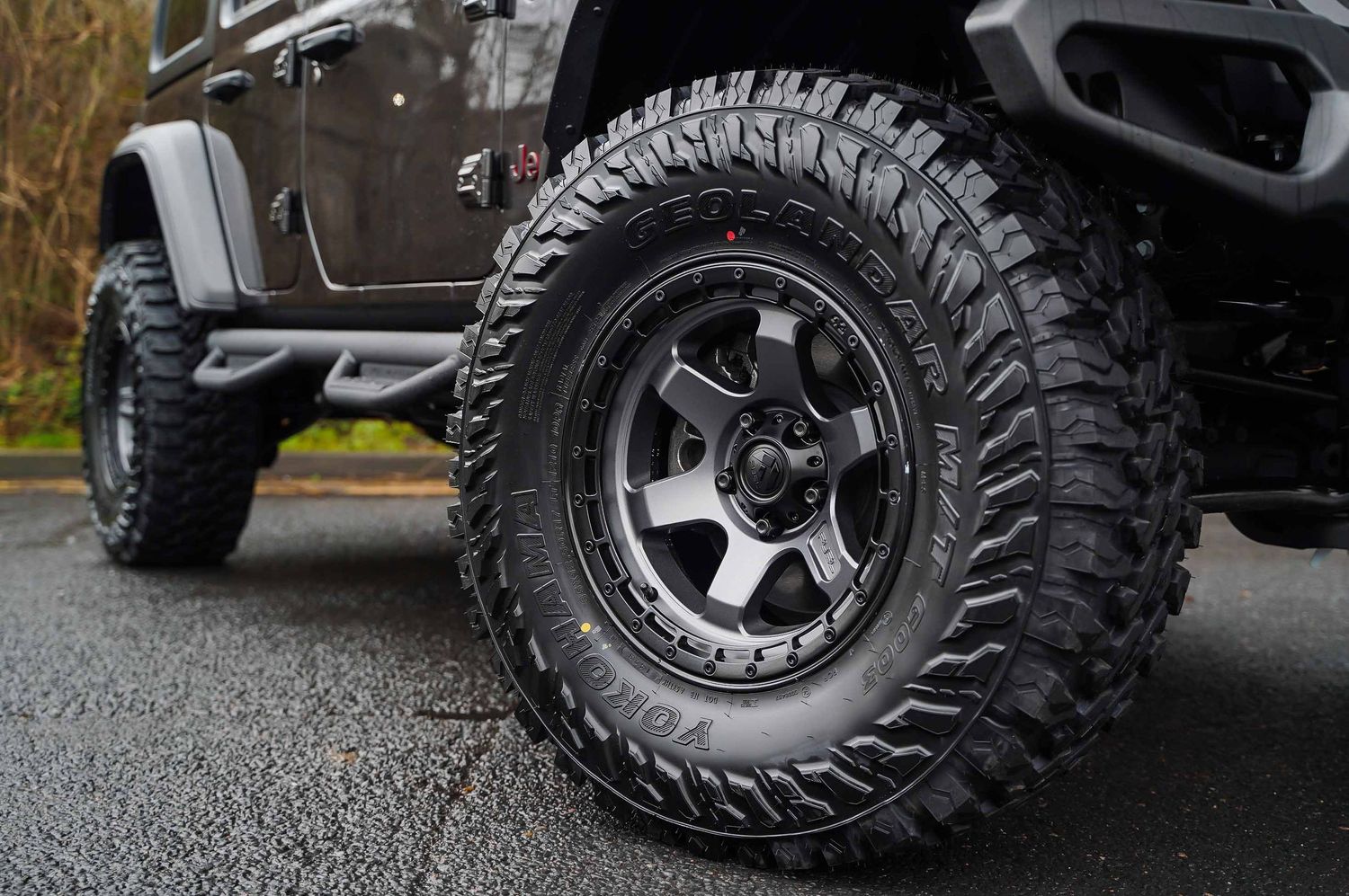 Close-up view of rugged off-road tires and black wheels mounted on a lifted vehicle.