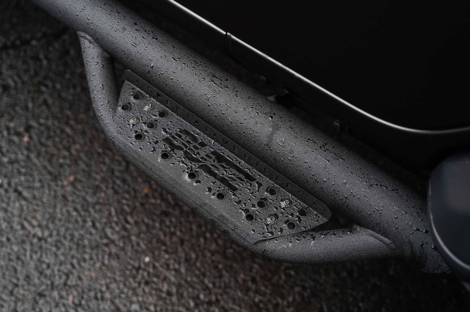 Black textured vehicle trim detail with water droplets in monochrome.