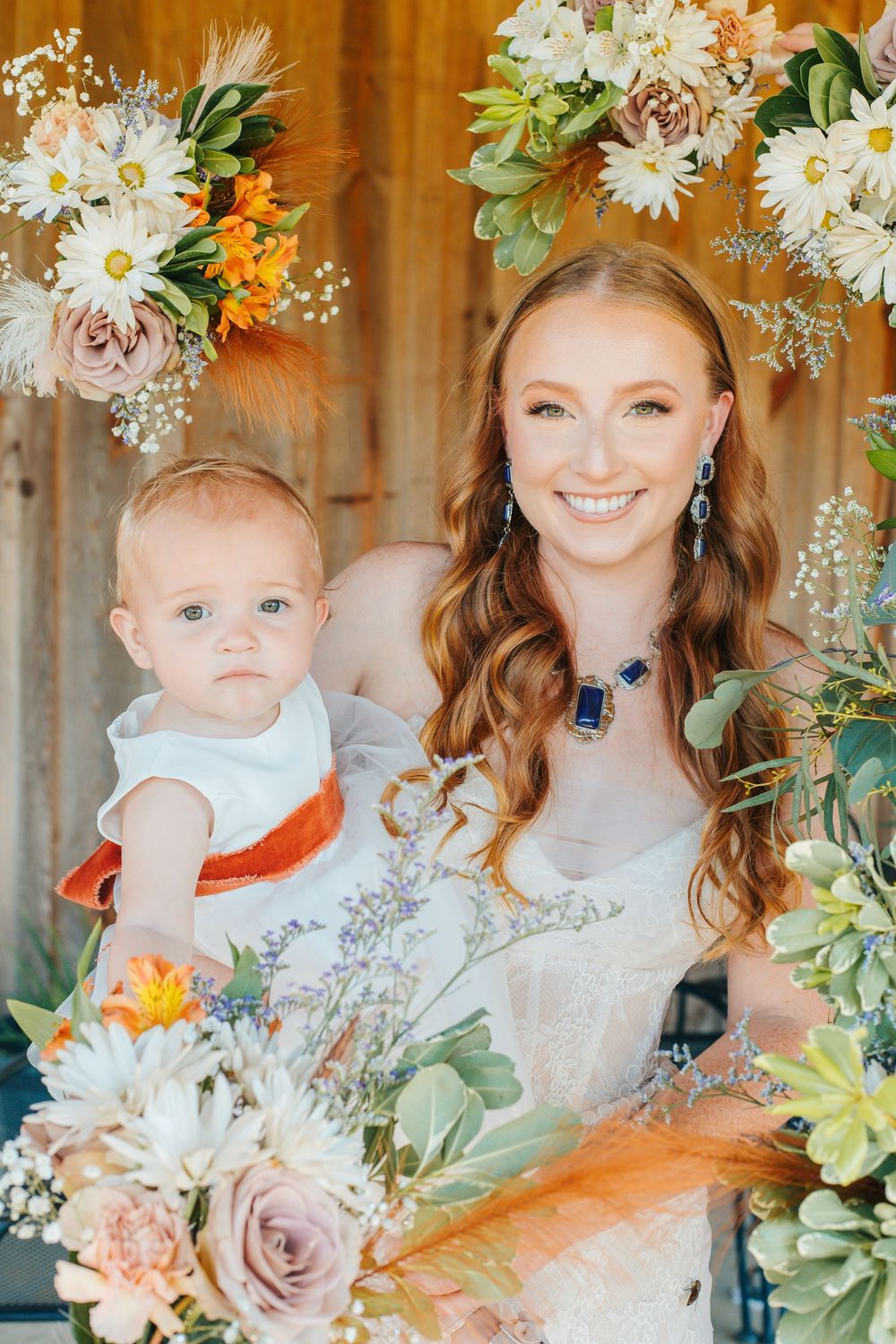 Floral wedding decorations featuring daisies, roses and succulents in soft peach and white tones.