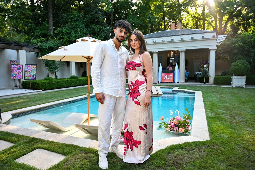 Couple celebrates their wedding day in a serene garden setting with a beautiful pool and umbrellas.