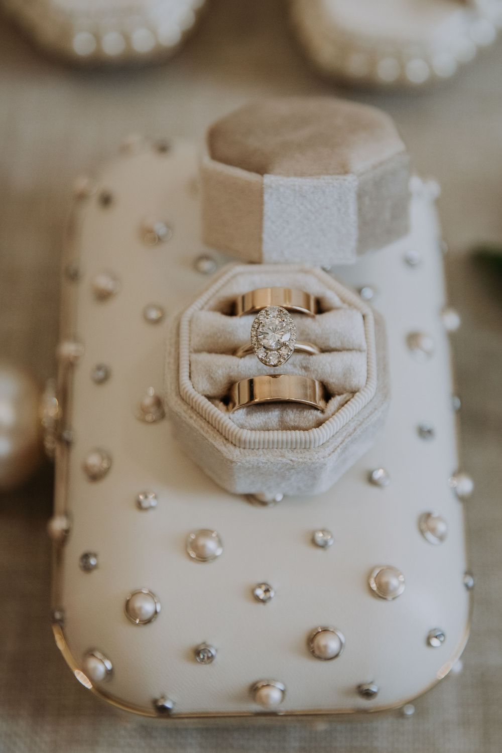 Close-up photo of elegant diamond engagement ring on textured white surface with pearl decorations.