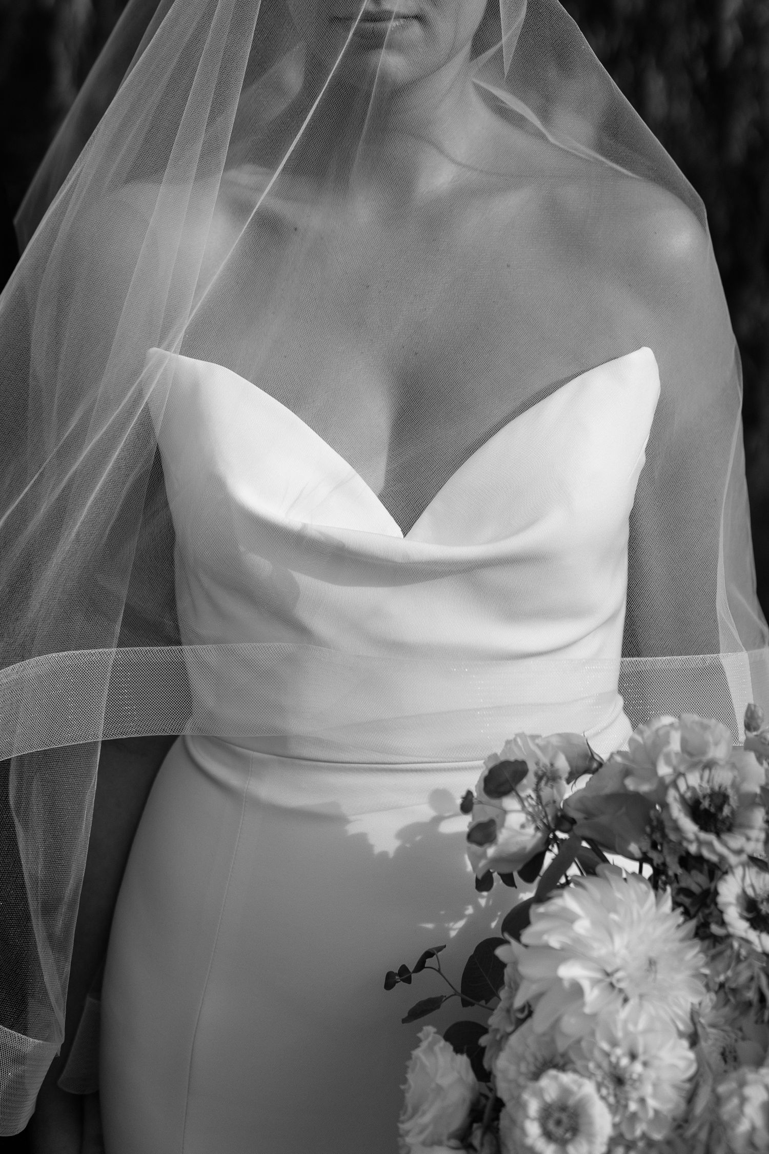 A black and white wedding photo series showing details of a bride's strapless dress bodice and floral bouquet.