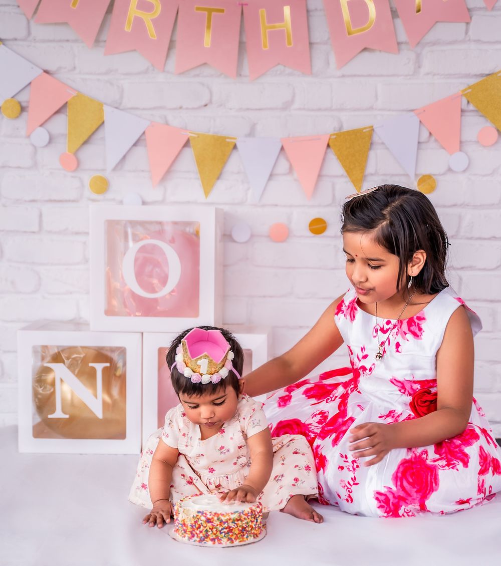 A birthday photoshoot setup with pink decorations and banners against a white brick wall.