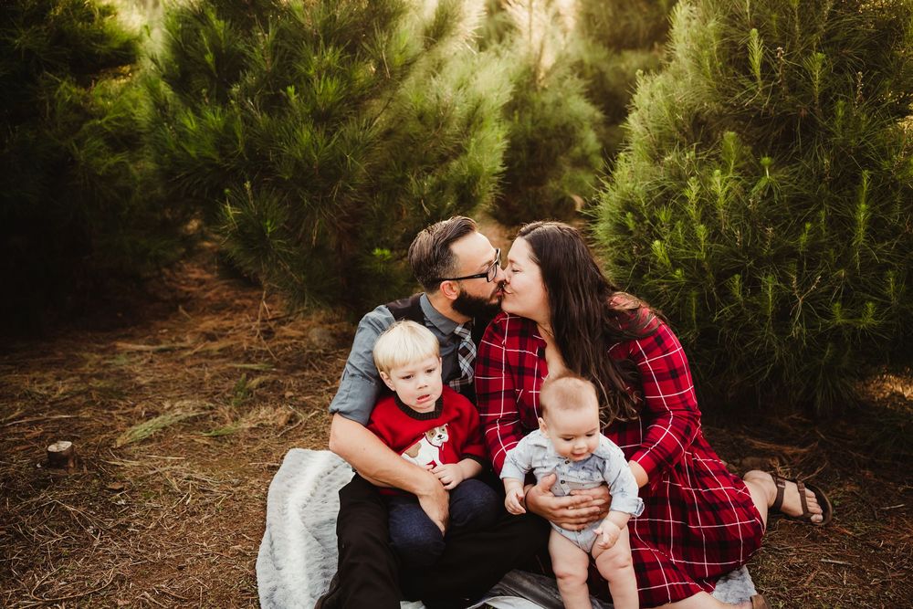 Family shares joyful moments together during an outdoor autumn photoshoot in a wooded setting.