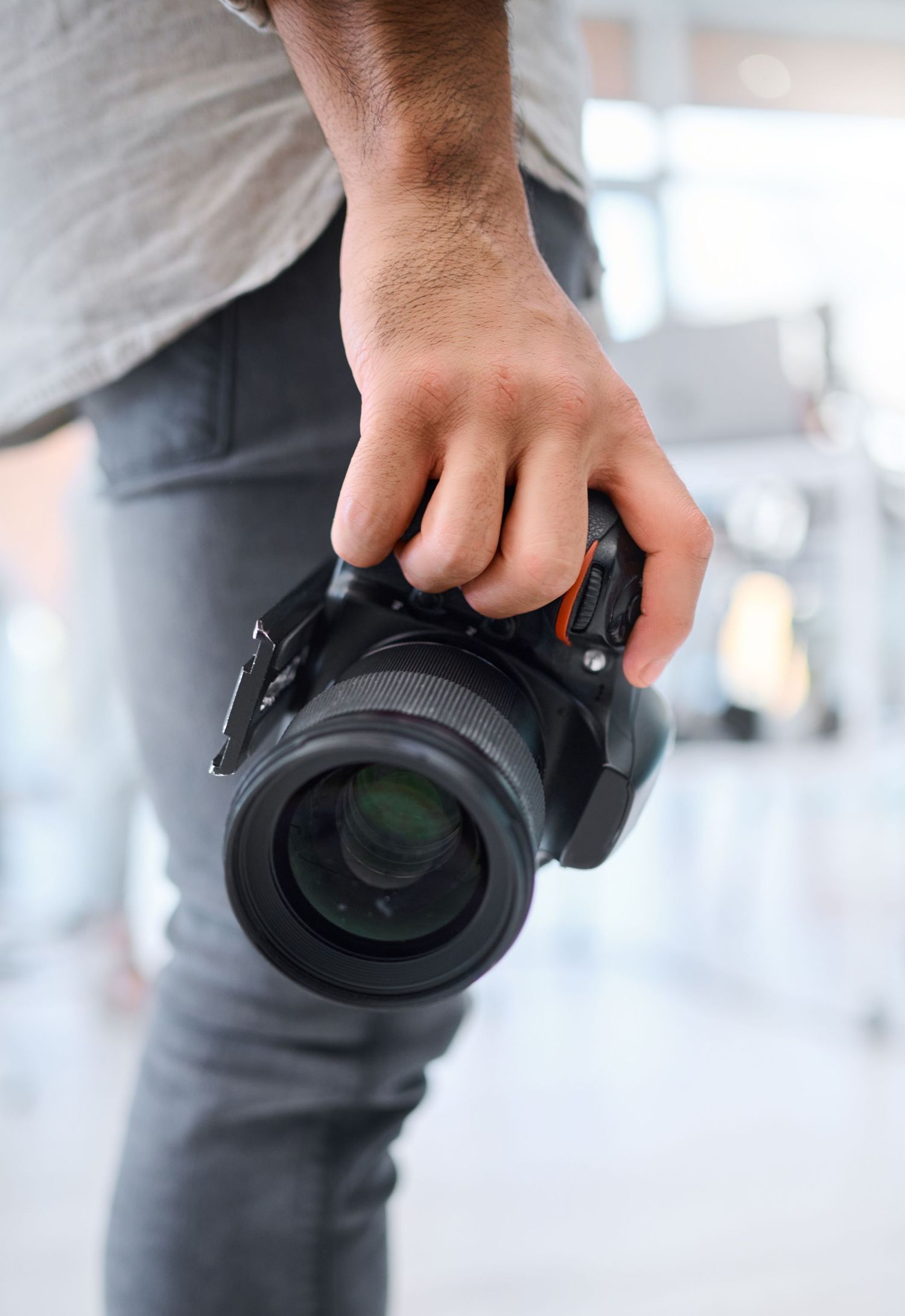 Close-up view of hands holding a camera lens at different angles in a light modern space.