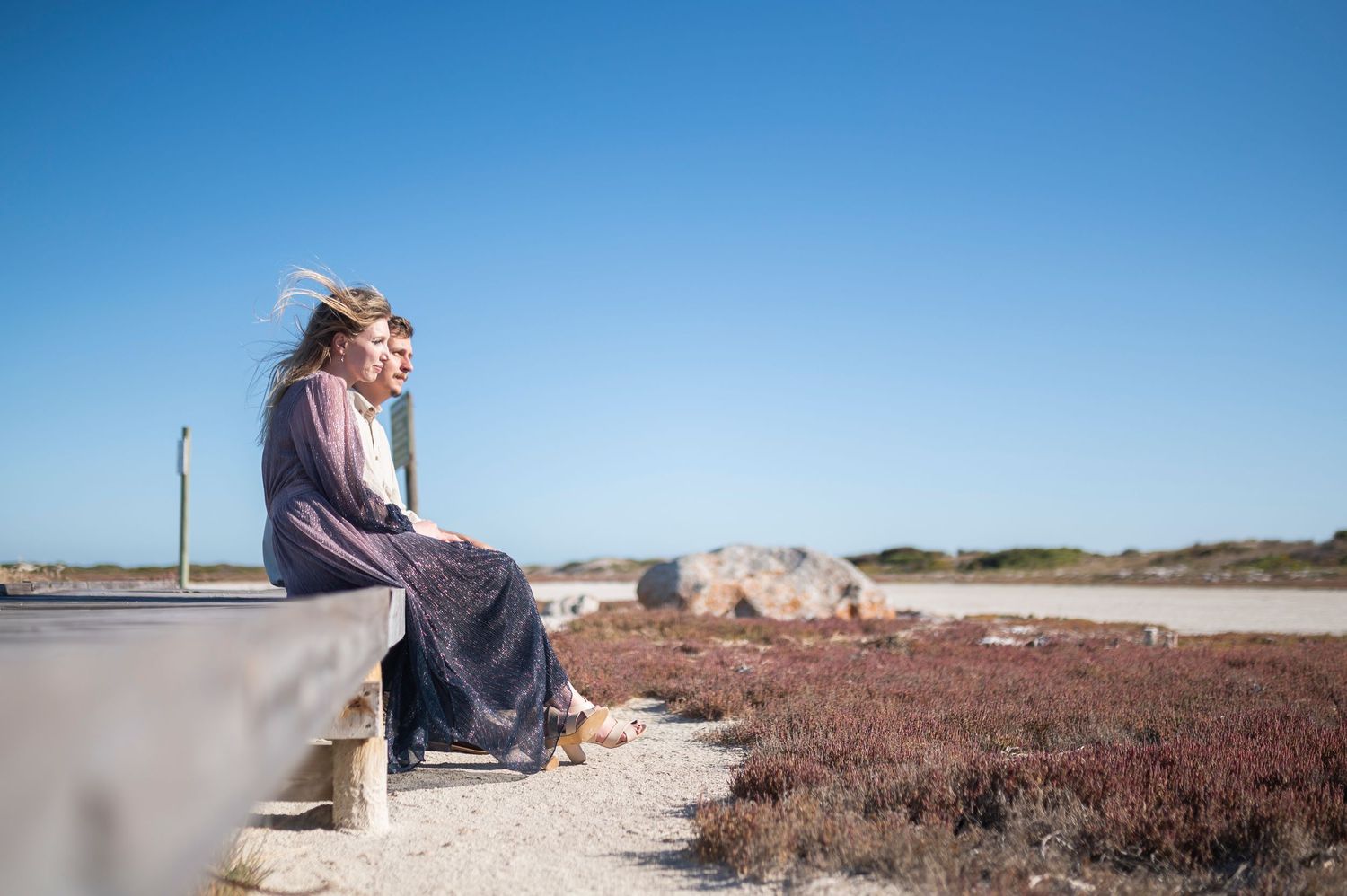 Happy couple enjoys a romantic sunset moment at a scenic sandy beach overlook on a clear summer day.