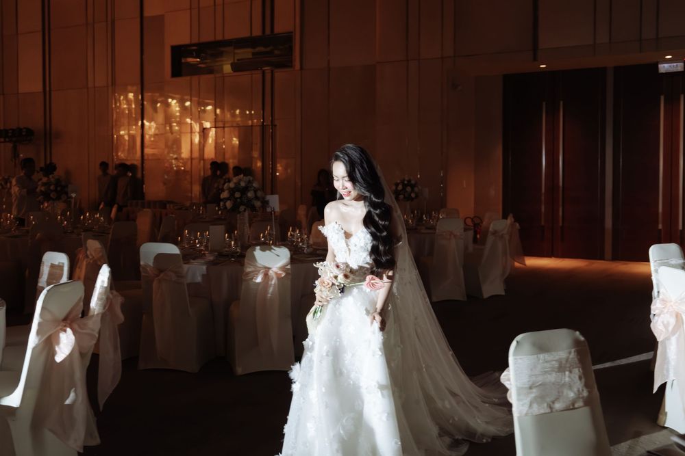A bride in a stunning white ball gown with veil walks through an elegant wedding reception venue.