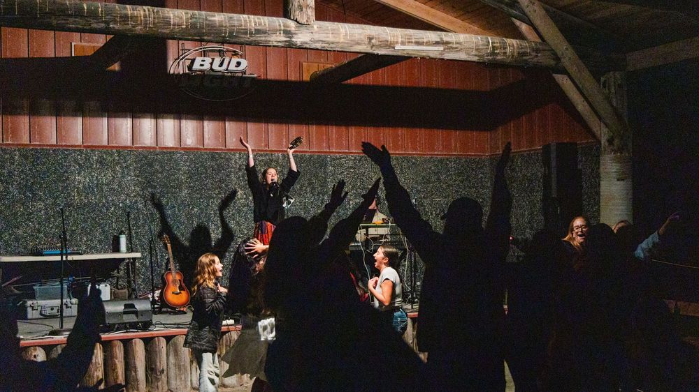 A historic rafter beam structure under warm lighting shows exposed wooden beams in a rustic interior ceiling.