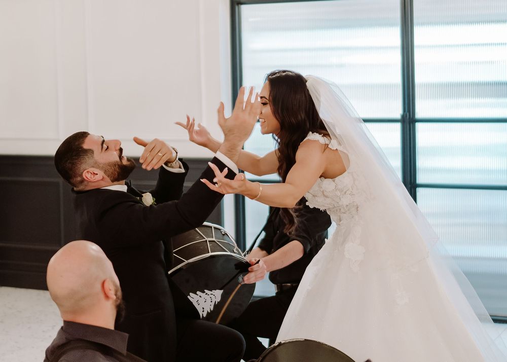 Wedding couple performing choreographed first dance in reception venue with water view.