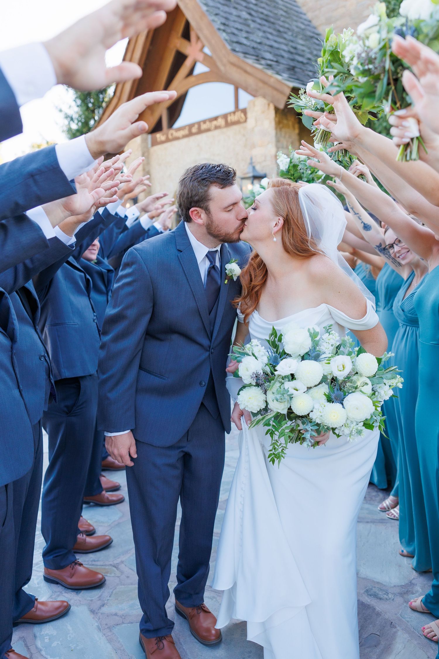 A romantic wedding exit line as a couple shares a kiss while guests form an aisle with flower petals at Integrity Hills at Big Cedar Lodge.