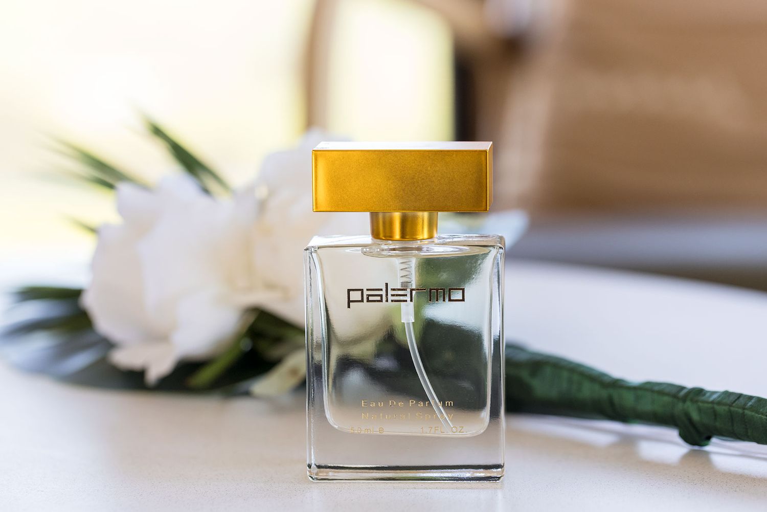 Yellow lids on clear perfume bottles displayed with white flowers on a light fabric surface.