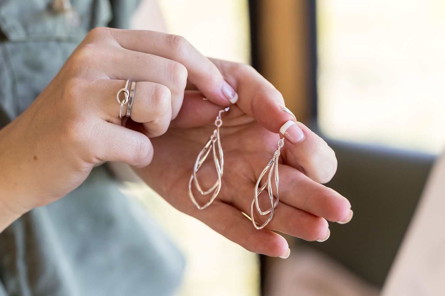 Delicate metal earrings being gently held between two fingers to showcase their elegant design details.
