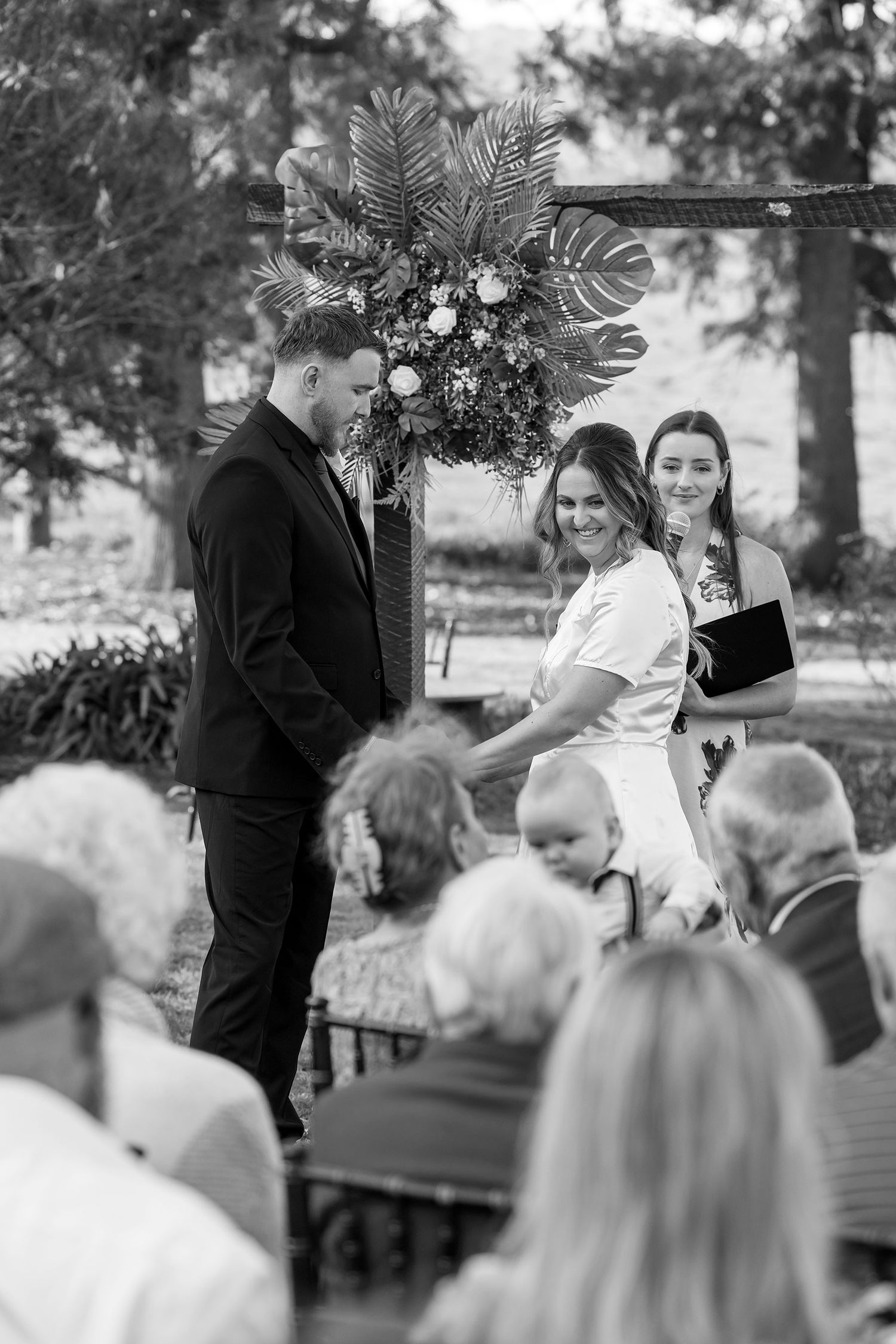 A black and white image of a  Bride and Groom sharing a moment together during their vows in their outdoor wedding ceremony at Kimo Estate.