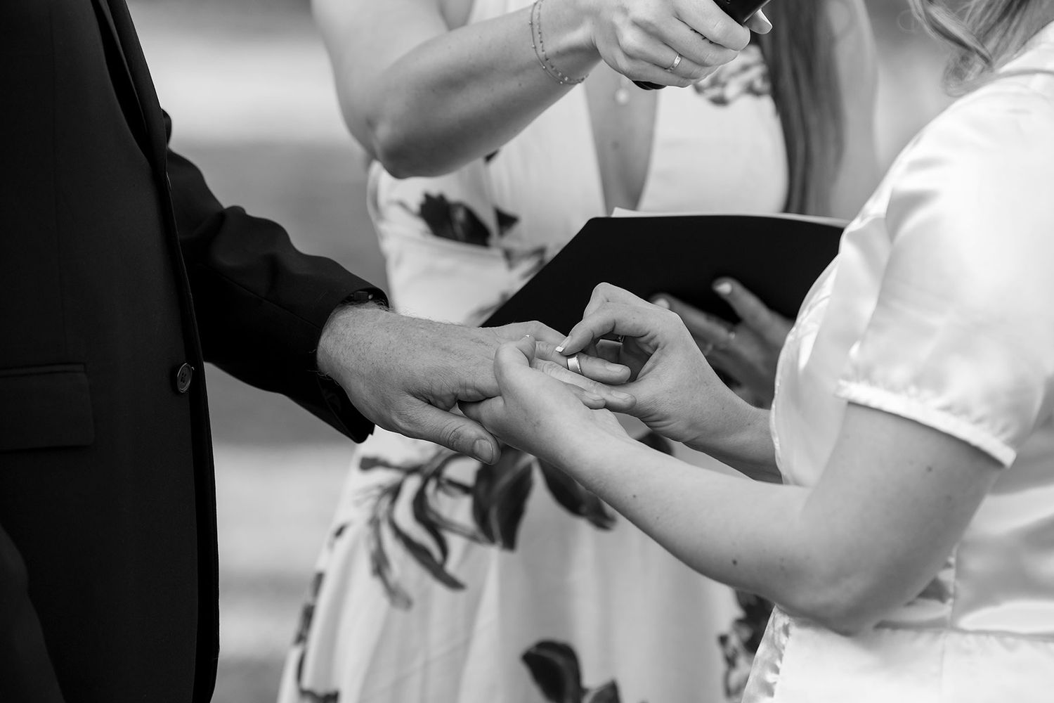 A black and white image of a  Bride and Groom exchanging rings together during their vows in their outdoor wedding ceremony at Kimo Estate.