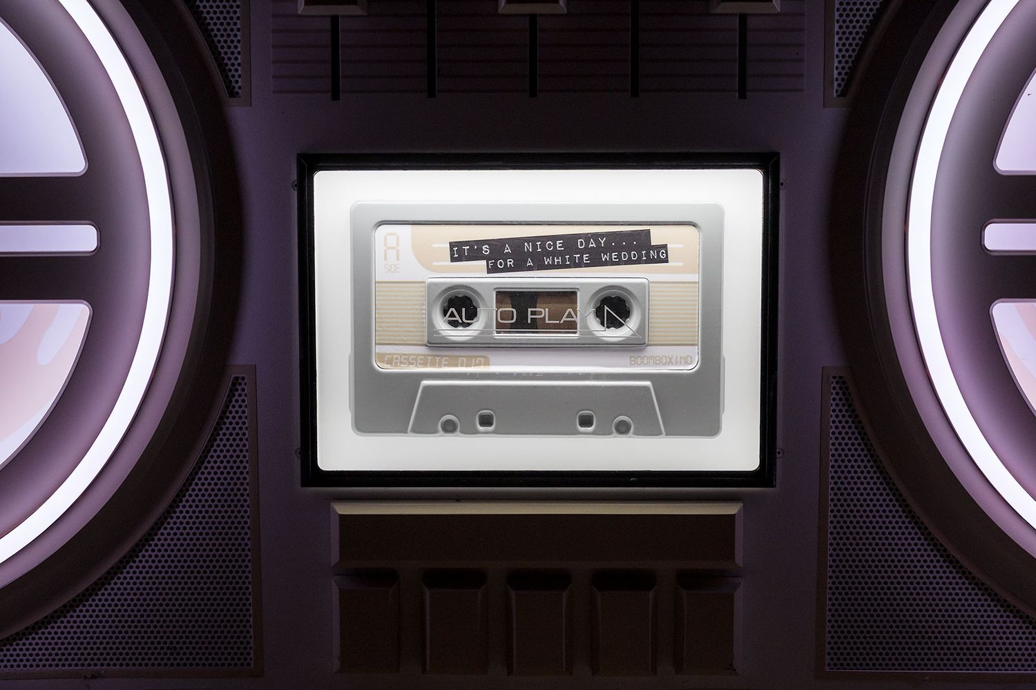 Vintage audio cassette tapes and packaging displayed against an illuminated purple and white circular light background.