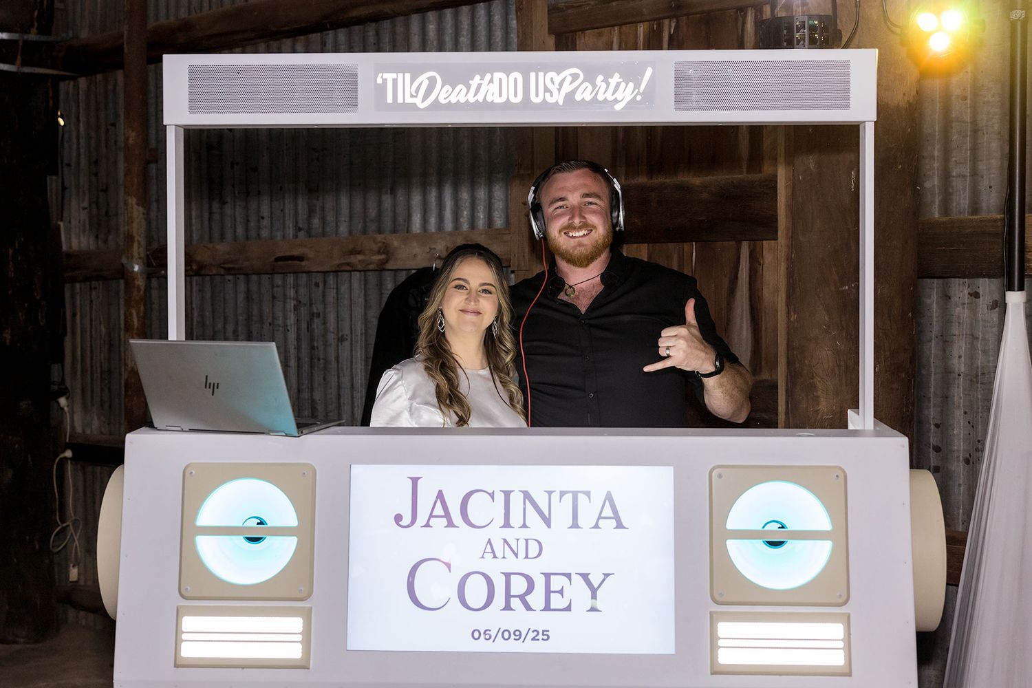The Bride and Groom standing behind the DJ Booth during their wedding reception in the Grain Shed at Kimo Estate Gundagai.