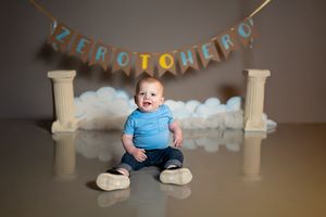 A decorative birthday setup with white balloons and pillars creates a festive backdrop for a celebratory photoshoot.