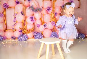 A child seated in front of pink floral decorations creates cascading artistic patterns through multiple photo exposures.