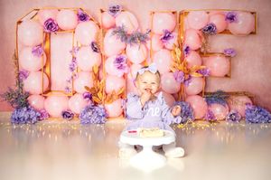 Pink and purple flowers arranged in floral chandeliers hang from a wedding venue ceiling creating a romantic ambiance.