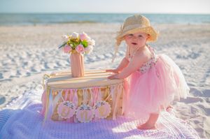 A series of beachside photos shows a pink tulle dress and floral decorations arranged at sunset along the sandy shore.