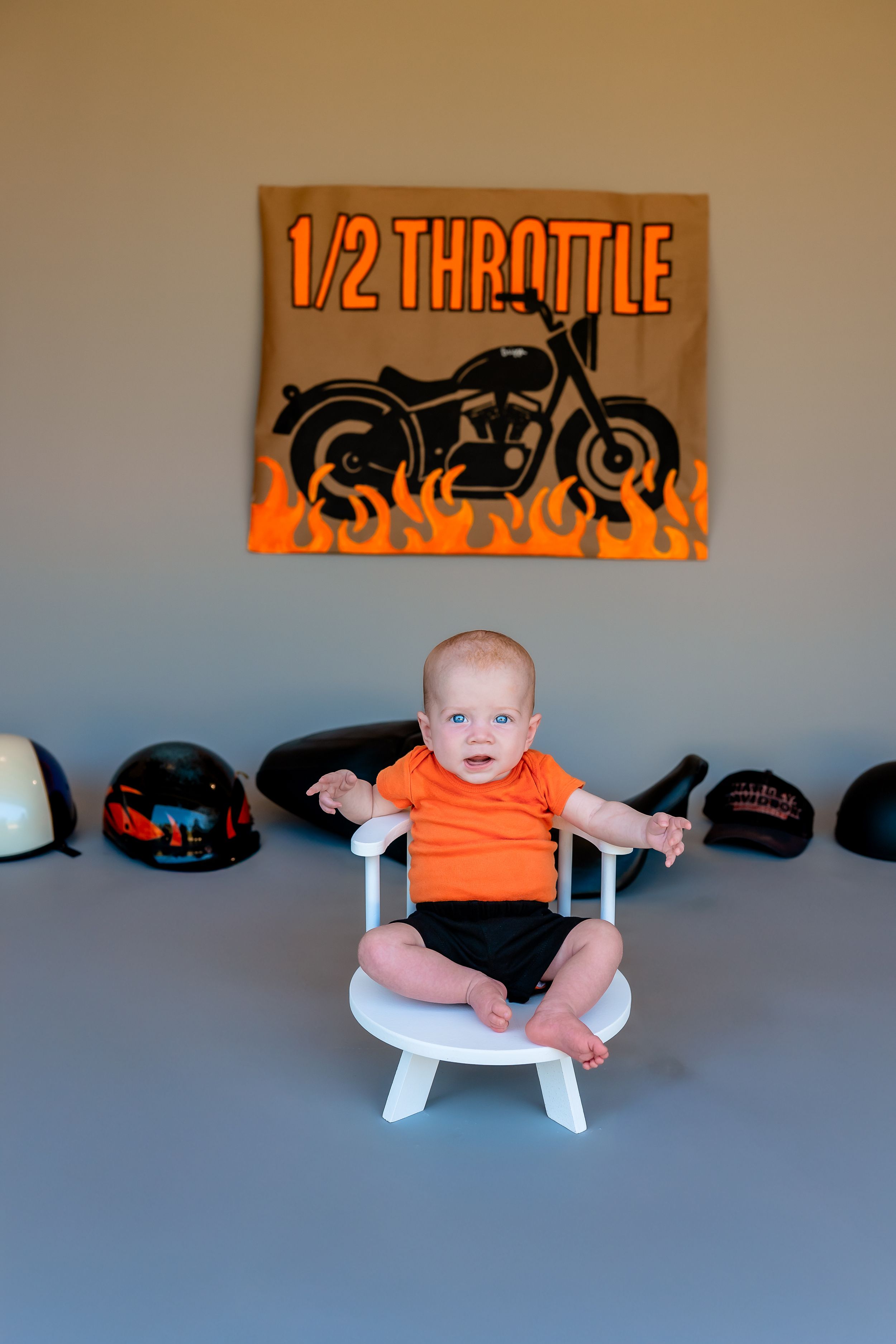A series of photos showing a baby in an orange onesie sitting on a white bench against a gray wall with motorcycle decor.