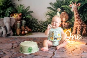 Baby's first birthday cake smash with jungle safari theme, giraffe and elephant decorations, neon One sign.