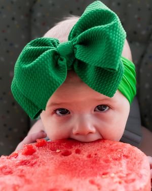 A sweet moment of joy showing a large red watermelon slice being enjoyed with a green bow accent.