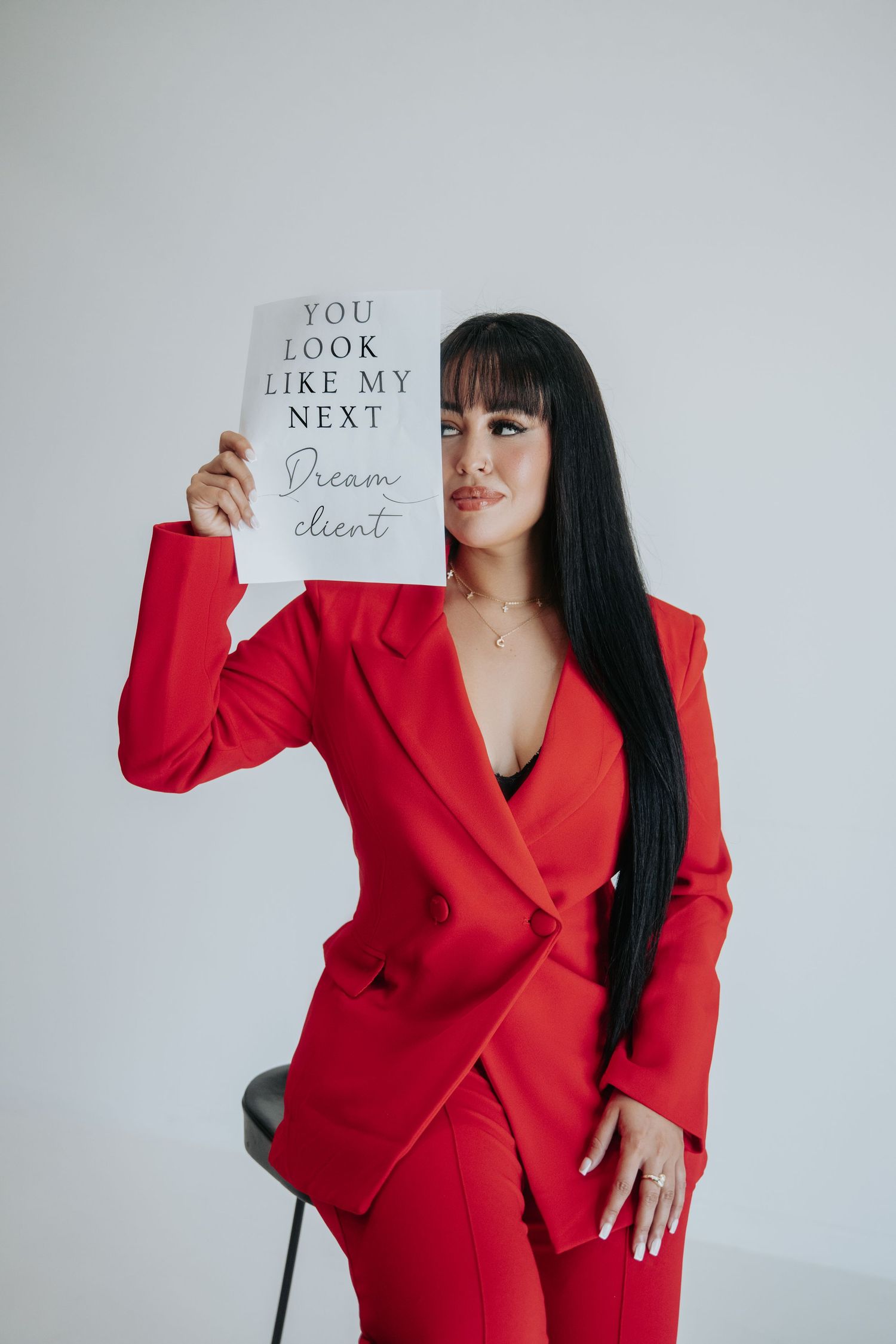 A figure wearing a bold red business suit poses against a white background holding up cards with text messages.