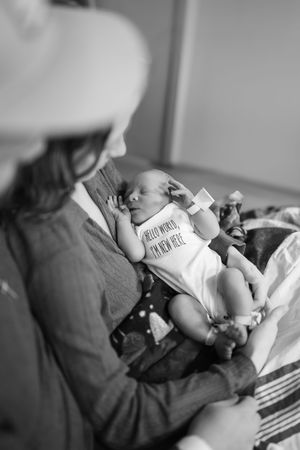 Black and white photo series showing a baby bottle feeding sequence in four connected frames.