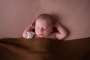 Seven connected newborn baby portraits showing different gentle poses on brown textured backgrounds.