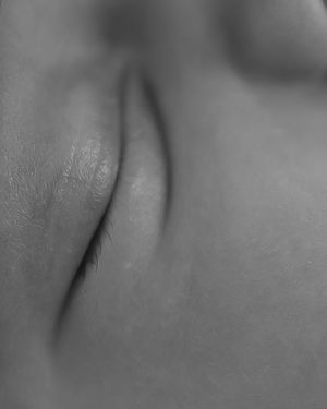 Extreme close-up black and white photograph showing soft skin texture with delicate shadows and curves.