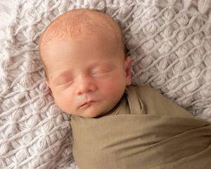 Newborn baby sleeping peacefully on textured gray blanket in series of connected photos.
