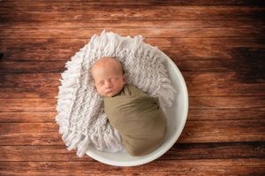 Six newborn photography scenes on rustic wood backdrop with infant posing on white textiles in neutral tones.