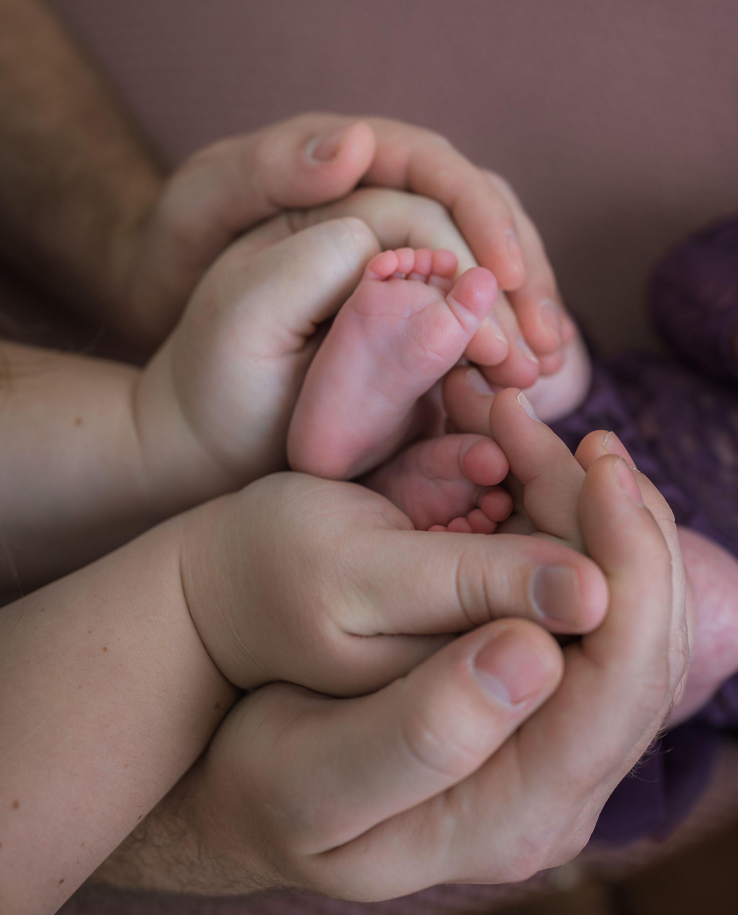 Close-up series of tiny baby fingers being gently held and cradled in adult hands.