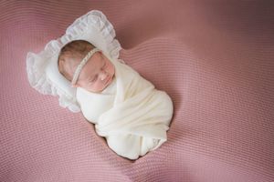 Seven small black and white cropped images of an infant resting on pink textured fabric.