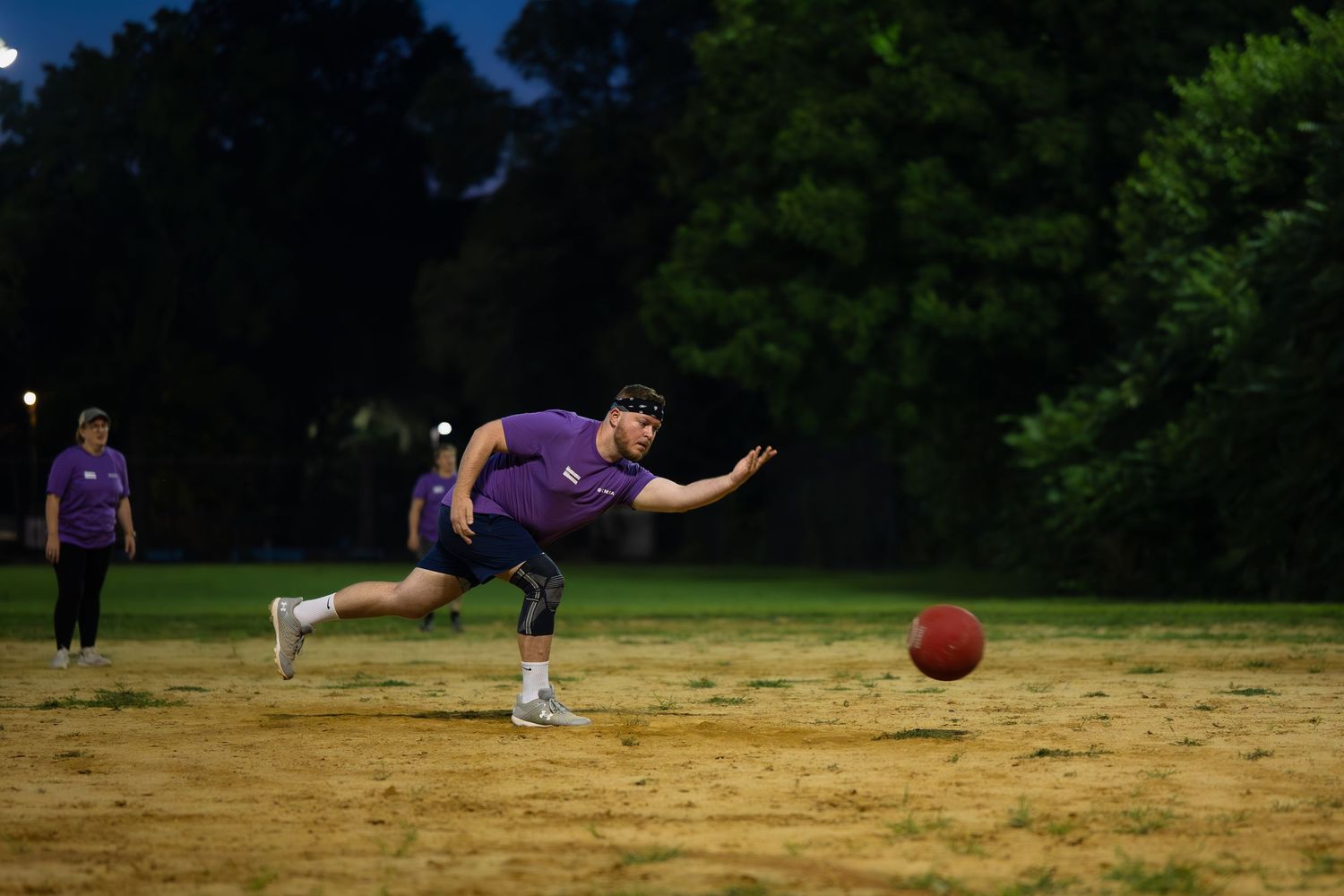 A kickball athlete pitches at dusk in a park in Chicago