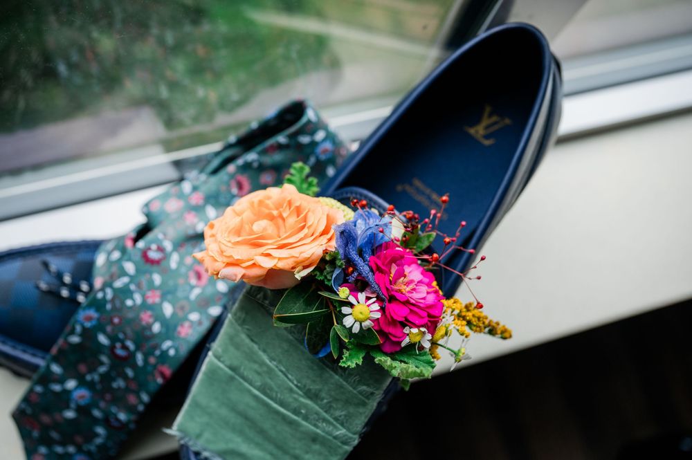 Decorative floral arrangement featuring orange and pink flowers placed inside a navy blue shoe.