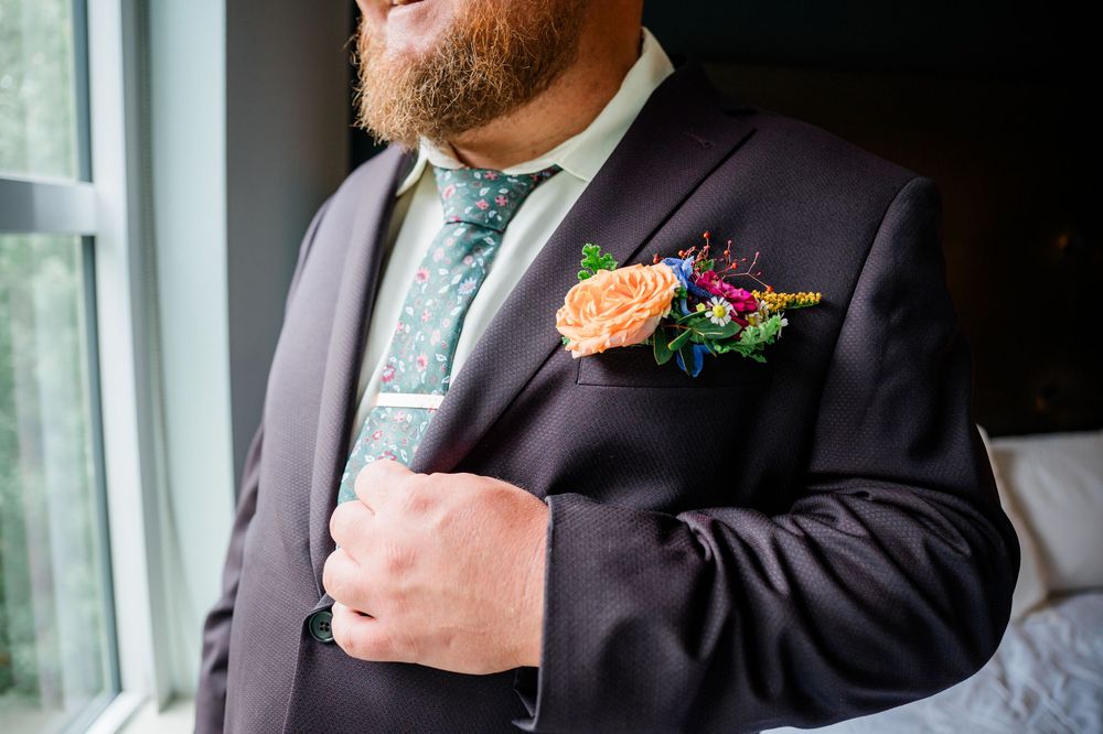 Close-up of formal suit jacket with boutonniere and tie detail.