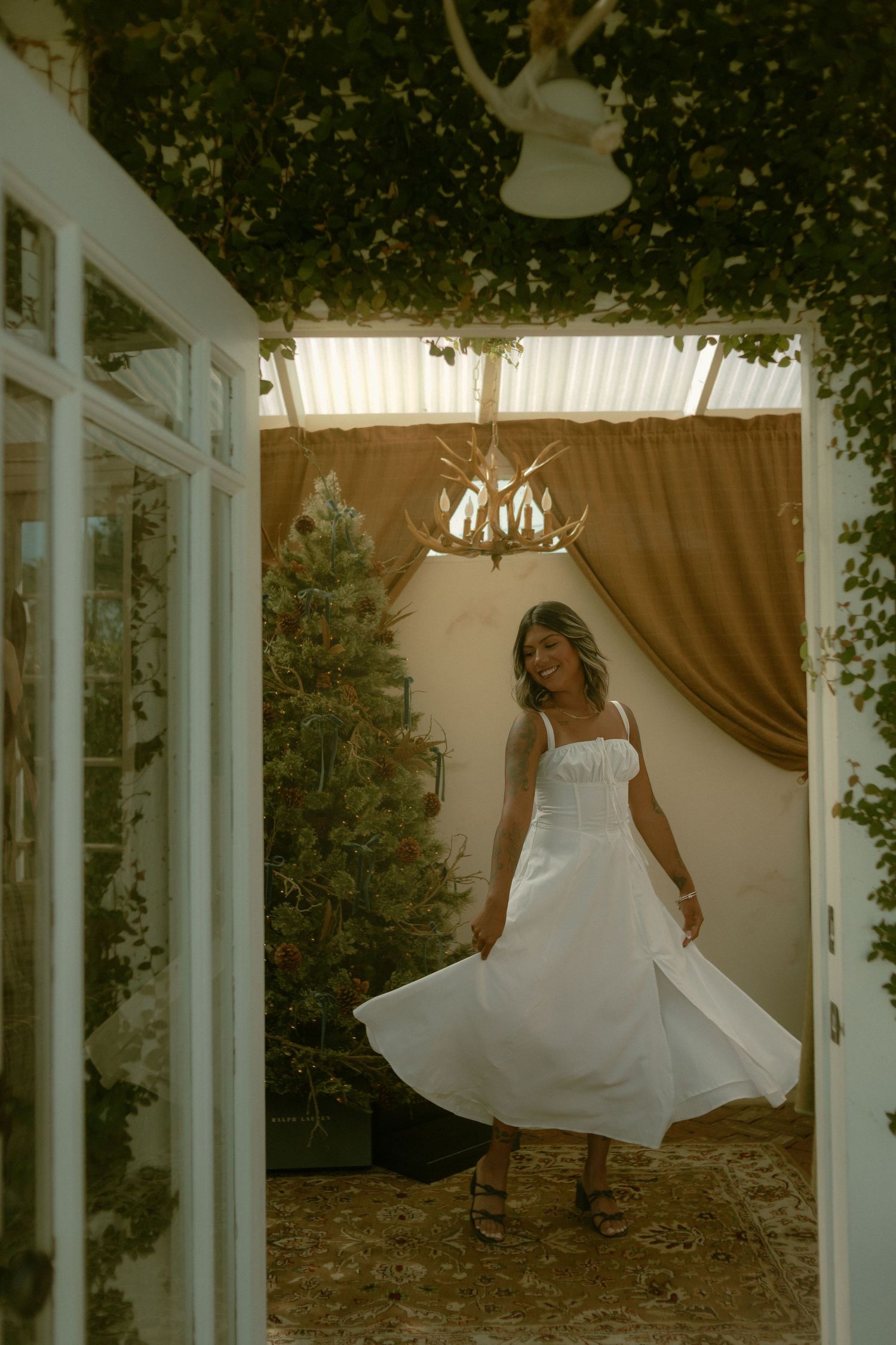 A white wedding dress twirls gracefully in the sunlit greenhouse in Whittier, California with green vines and vintage decor.