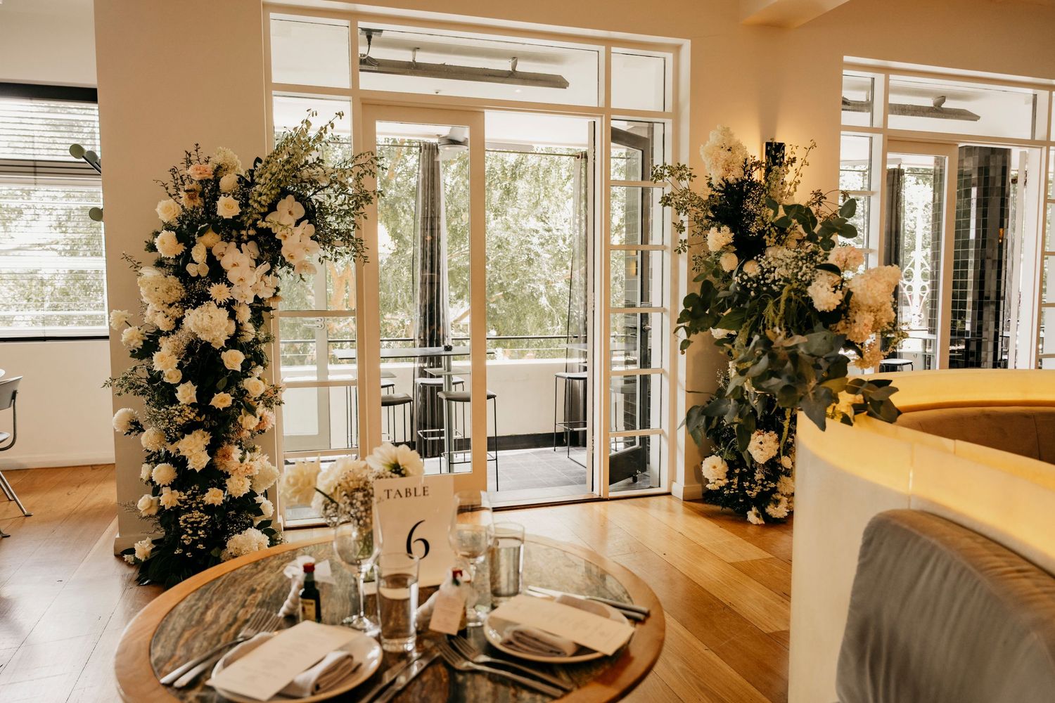 Modern white kitchen with open concept design features stainless appliances, marble countertops and elegant floral arrangements.