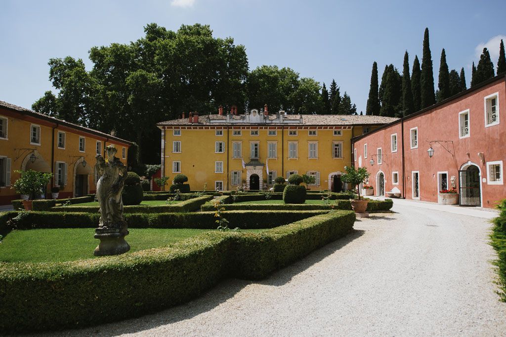 A peaceful garden path leading to a rustic Italian villa with cypress trees and manicured hedges in Tuscany.