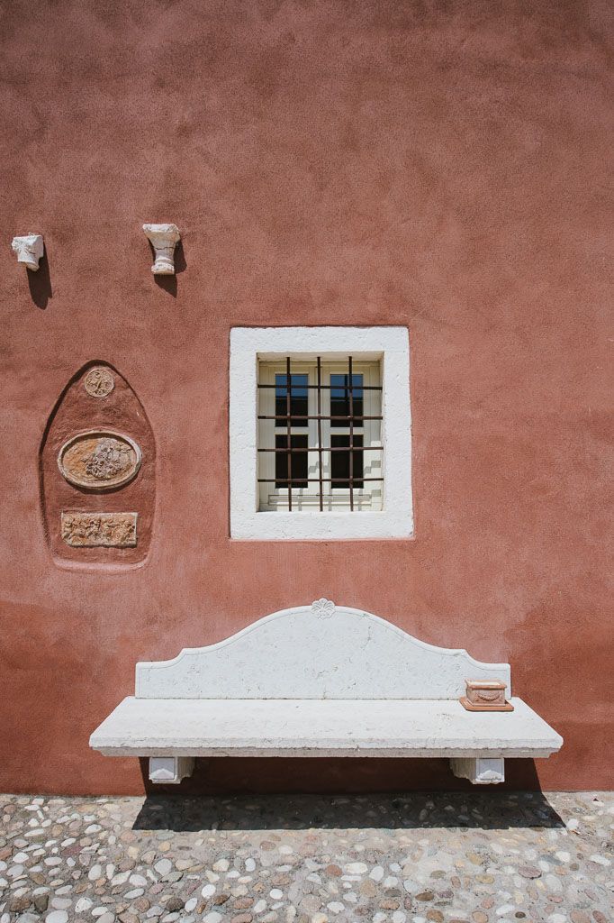 A rustic terracotta wall with white-trimmed windows and decorative stone medallions creates a classic Mediterranean facade.