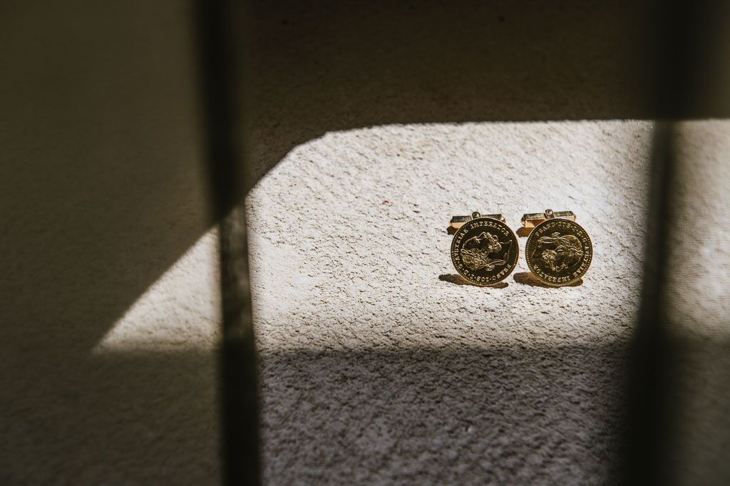 Two gold wedding bands cast dramatic shadows in natural sunlight on a white textured surface.