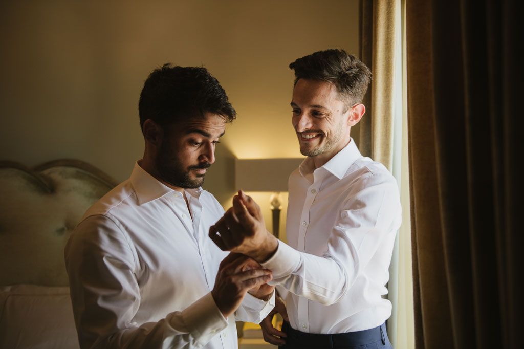 Four candid moments show two men in white shirts laughing and embracing in warm, natural light.