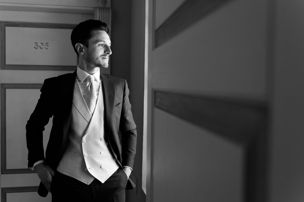 Elegant black and white portrait photograph of someone wearing a formal suit and bowtie against a textured background.