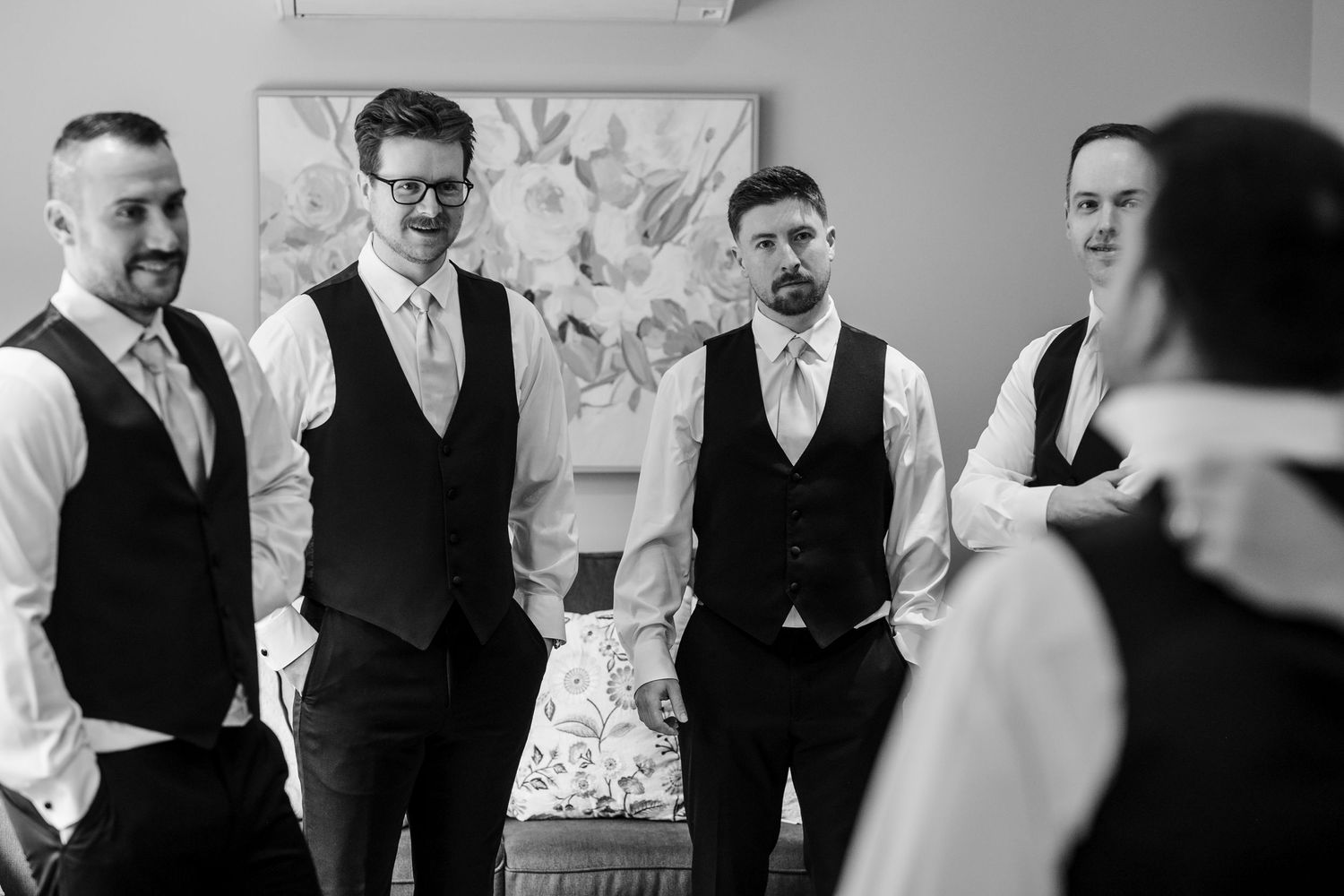 A black and white photo of a groomsmen group wearing vests standing together before a wedding ceremony.