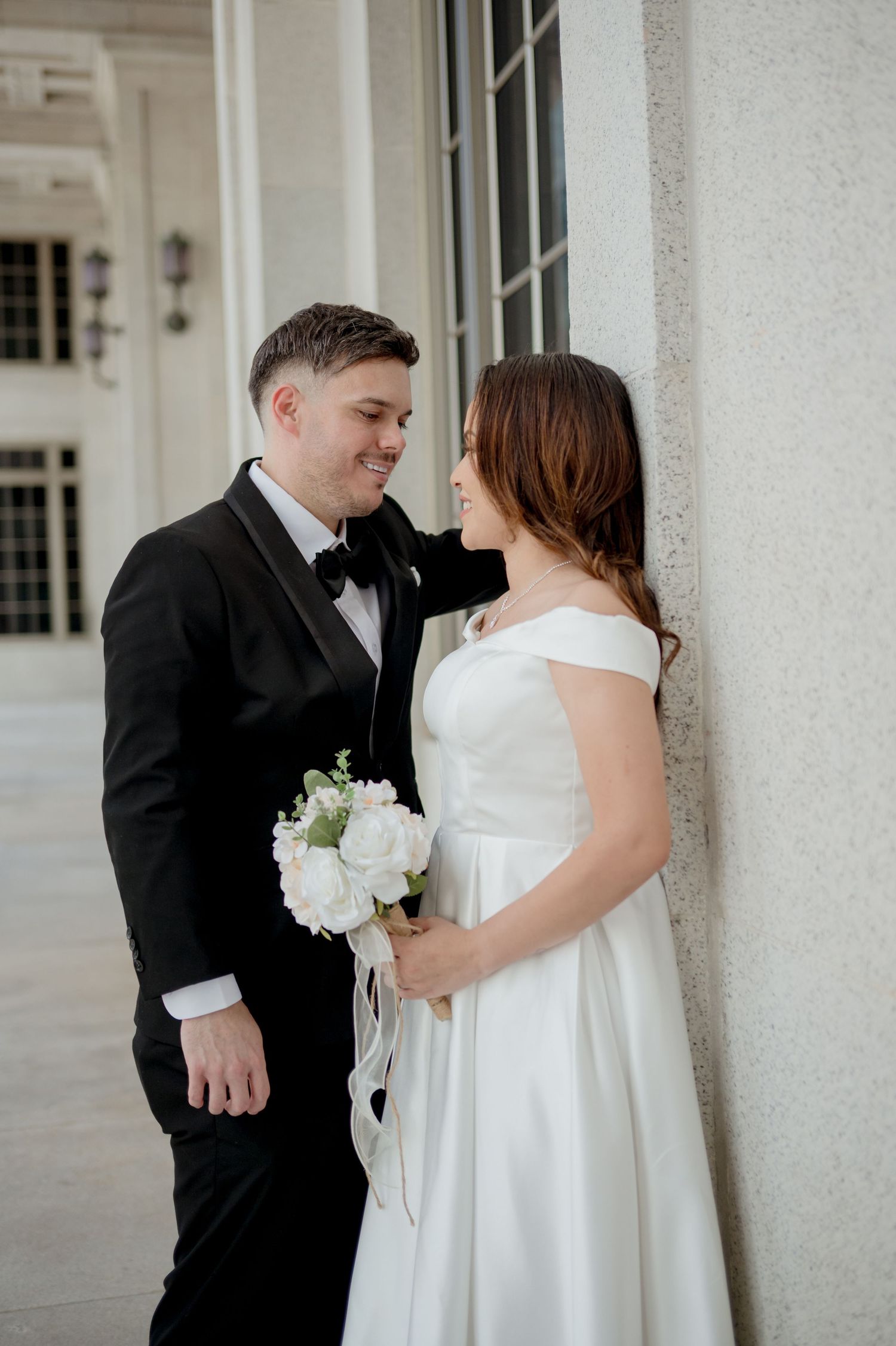 A couple in wedding attire share joyful moments in a series of photos against white columns.